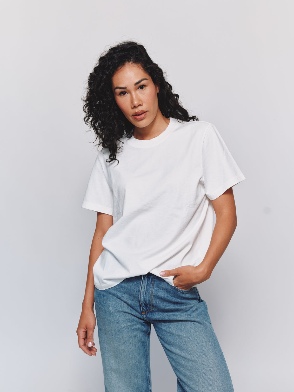 Model wearing size S in an oversized white t-shirt and blue jeans against a light gray background