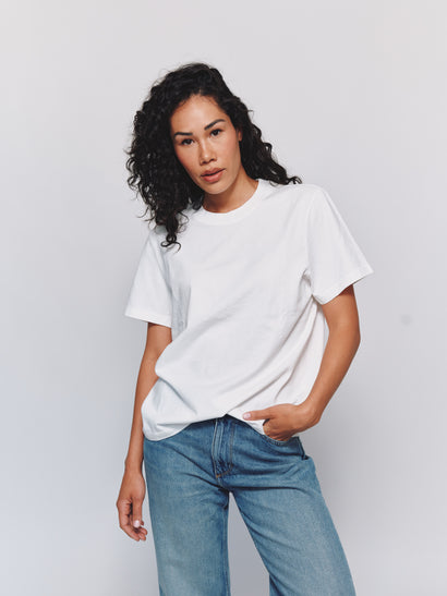 Model wearing size S in an oversized white t-shirt and blue jeans against a light gray background