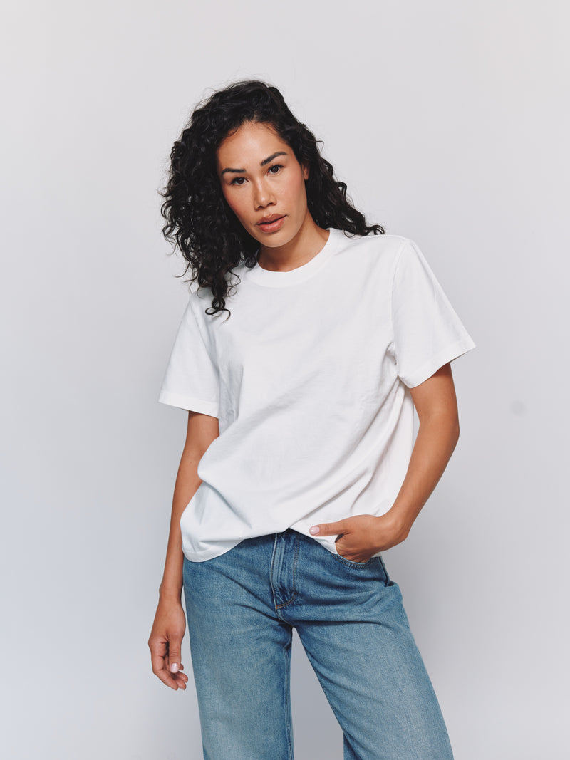 Model wearing size S in an oversized white t-shirt and blue jeans against a light gray background