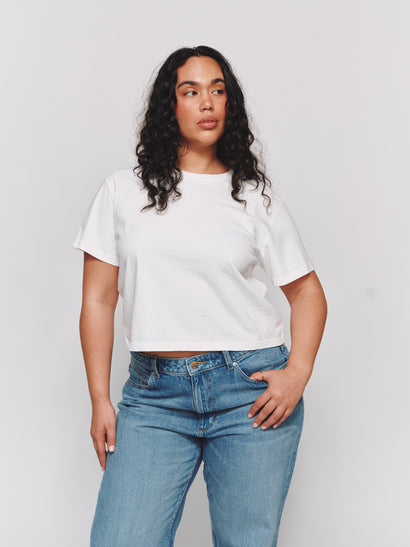 Model wearing size L in a relaxed cropped white t-shirt and blue jeans against a light gray background